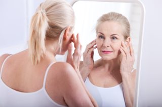 Forty years old woman looking at wrinkles in mirror. Plastic surgery and collagen injections. Makeup. Macro face. Selective focus on the face