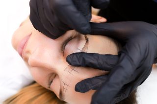 the permanent makeup artist stretches the skin in the area of the eyebrows to perform the tattoo